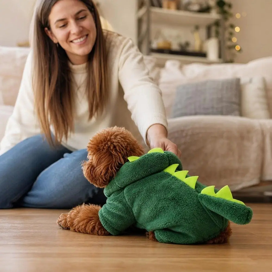 Woman smiling at her dog in the Dino Hoodie on the living room floor