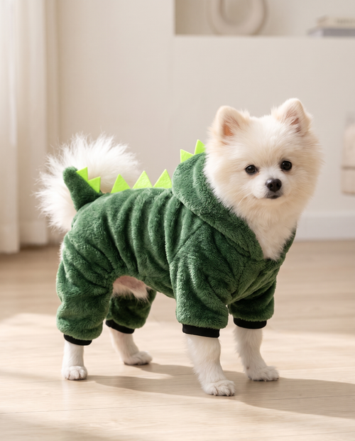 White fluffy dog in the Dino Hoodie at home, showing the spiky back and tail